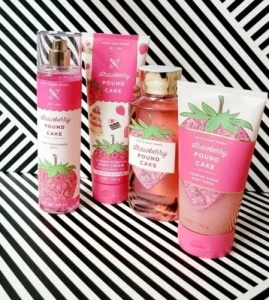 Strawberry Pound Cake body care products arranged with pink packaging on a black-and-white striped background.