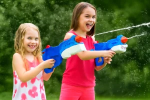 Best water guns for kids, two girls having fun with colorful water guns on a sunny day.