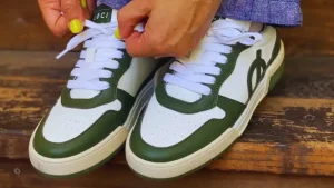 Tying green and white LOCI sneakers