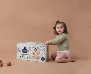 Toddler with Millie Moon diapers box showcasing luxury diaper packaging and comfort.