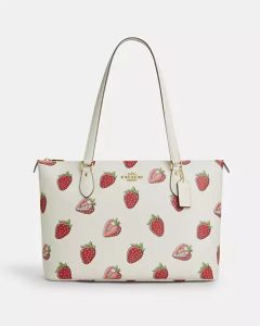 Coach handbag featuring a playful strawberry print with gold accents and detachable strap.
