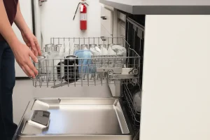 Person loading clean dishes in dishwasher